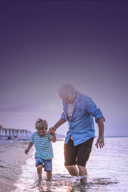 Bild: Ein Mann spaziert mit einem Kind am Meer, Hand in Hand